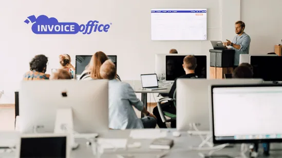 The Invoice Office team at work in the office, with the Invoice Office logo on the wall and the invoicing software on screen